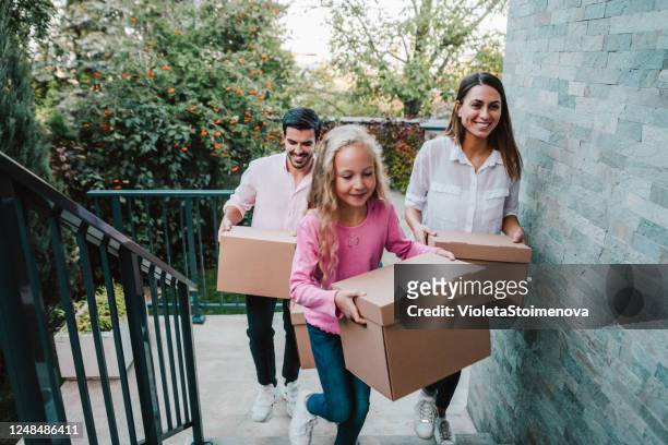 glimlachende familie die dozen in hun nieuw huis draagt. - family tree stockfoto's en -beelden