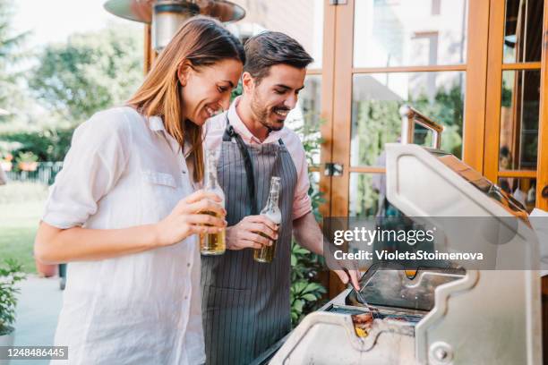 young couple making barbecue in their garden. - couple grilling stock pictures, royalty-free photos & images