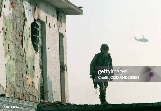 Soldier walks on the roof tiles of a bombed out house, which used to be a cafe, in the bufferzone dividing Serb held Posavina corridor and Bosnian...
