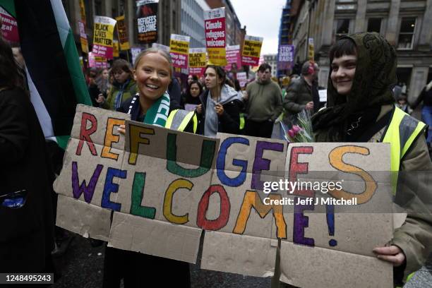People with a placard saying "Refugees Welcome!" march during a Stand Up To Racism protest at George Square on March 18, 2023 in Glasgow, Scotland....