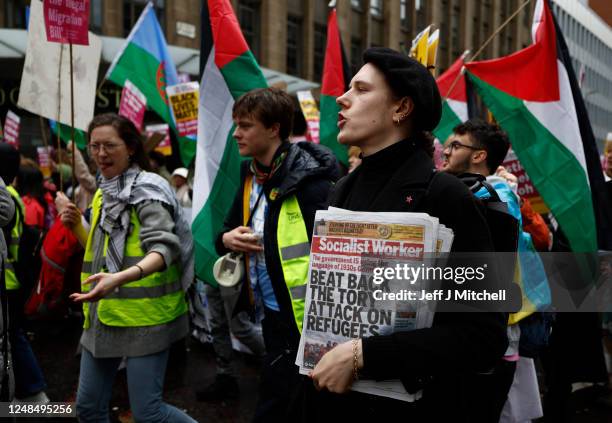 Protester carries a copy of the Socialist Worker during a march during a Stand Up To Racism protest at George Square on March 18, 2023 in Glasgow,...