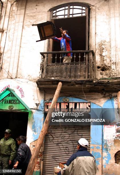 Man seen throwing out ruined furniture from the storms, 20 February 2002 in La Paz. Un hombre arroja una mesa desde la ventana de una casa afectada...