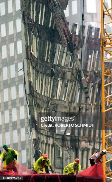 Workers hang a safety net to protect a building adjacent to the wreckage of the World Trade Center 20 September 2001 in New York, nine days after the...