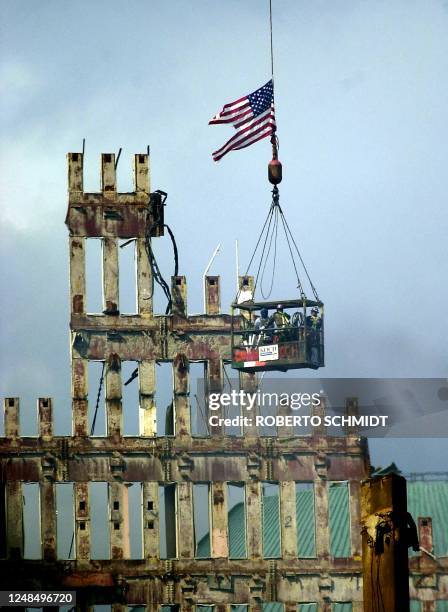 Workers ride a basket over the remains of the World Trade Center in lower manhattan 29 September 2001 eighteen days after the financial complex was...