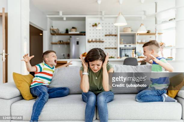 unhappy mother having problem with noisy naughty two kids - tantrum stock pictures, royalty-free photos & images