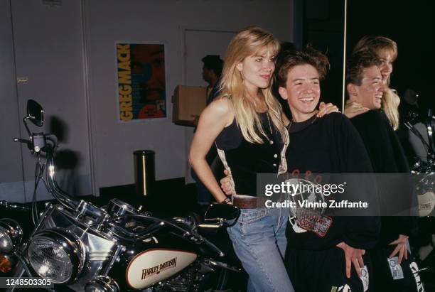 American actress Christina Applegate and American actor David Faustino smiling as they pose beside a Harley-Davidson motorcycle on the occasion of...