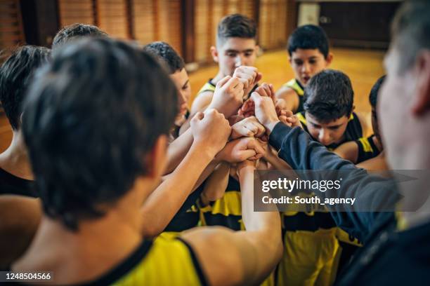 group of teenage boys basketball players with their coach huddling before match - recreational sports league stock pictures, royalty-free photos & images