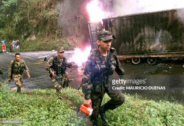 Military soldiers disperse throughout the area where guerrilla soldiers destroyed supply trucks in Buga, Colombia 10 April 2003. Officials remain...