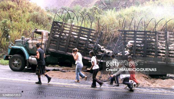 Farmers are seen walking by a truck destroyed by guerrilla soldiers in Buga, Colombia 10 April 2003. The guerrilla forces have given little answers...