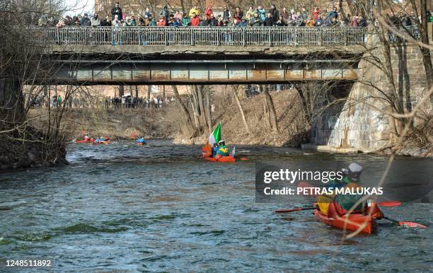 People canoe on the Vilnia river, which has been coloured in green to mark Saint Patrick's Day, on March 18, 2023 in Vilnius, Lithuania. - St...