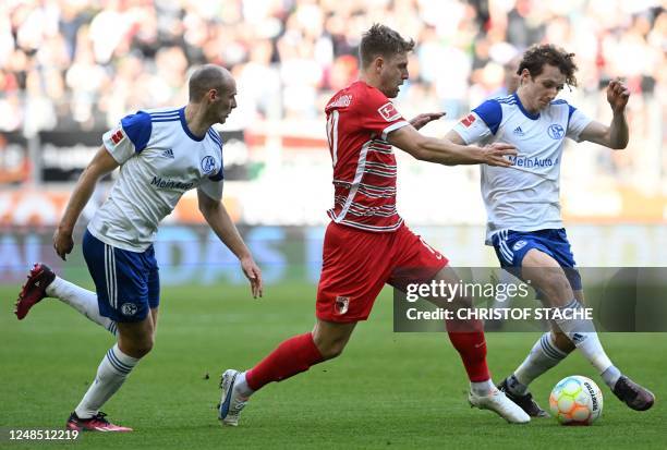 Schalke's German defender Henning Matriciani, Augsburg's German midfielder Arne Maier and Schalke's Czech midfielder Alex Kral vie for the ball...