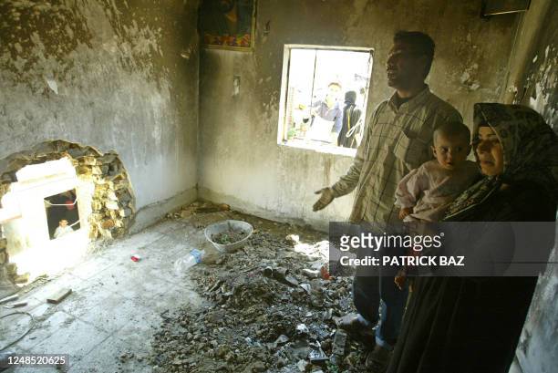 Hafez Elwan, his wife May and his 15 month-old daughter Fatima, stand 06 April 2004 in their destroyed bedroom after miraculously escaping a US army...