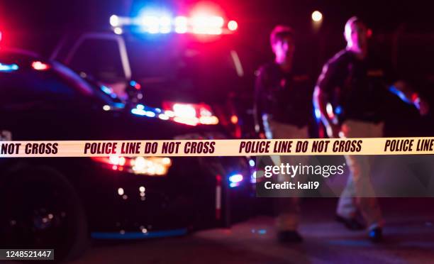 two police officers behind crime scene tape - fita delimitadora imagens e fotografias de stock