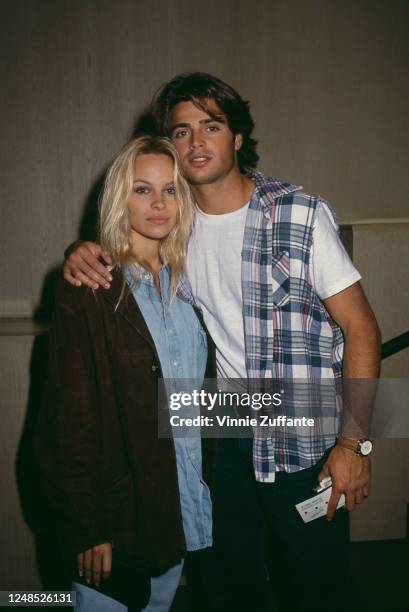 Canadian actress Pamela Anderson, wearing a dark jacket over a denim shirt, with French actor David Charvet, who has his arm around Anderson's...