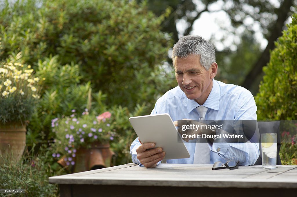 Business man in garden using digital tablet.