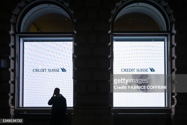 Man smokes next to light panel with the Credit Suisse logo at the headquarters of Credit Suisse bank in Zurich on March 18, 2023. - Switzerland's...