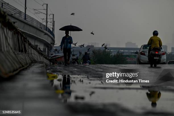 Commuters out during heavy rain at Akshardham Flyover on March 18, 2023 in New Delhi, India.