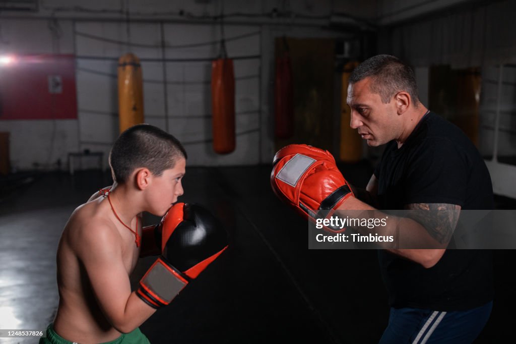 Boy training kickboxing with trainer