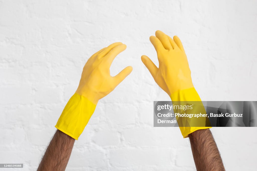 A man's hand with yellow rubber gloves