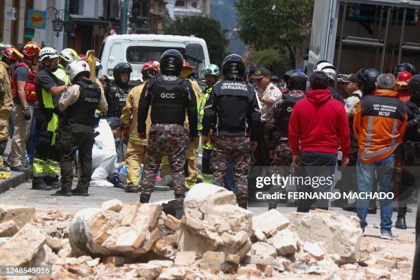 Soldiers and firefighters work at the place where the cornice and terrace of a building located in Cuenca's historic center fell and destroyed a car,...