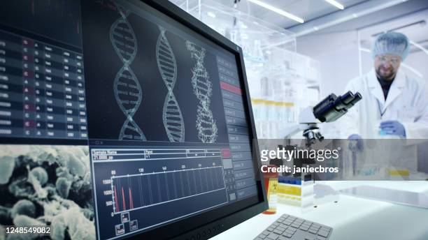 man working on laboratory equipment. dna research on computer screens - genetic screening stock pictures, royalty-free photos & images