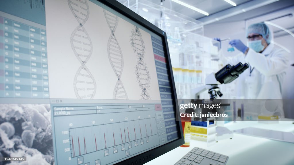 Uomo che lavora su attrezzature da laboratorio. Ricerca sul DNA sugli schermi dei computer