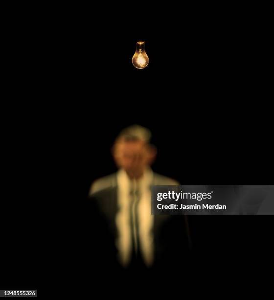 defocused mistery man in dark under light bulb - villain stock pictures, royalty-free photos & images