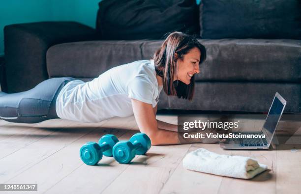 sporty woman exercising at home. - exercise computer stock pictures, royalty-free photos & images