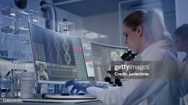 female research team studying dna mutations. computer screens with dna helix in foreground - dna test stock pictures, royalty-free photos & images