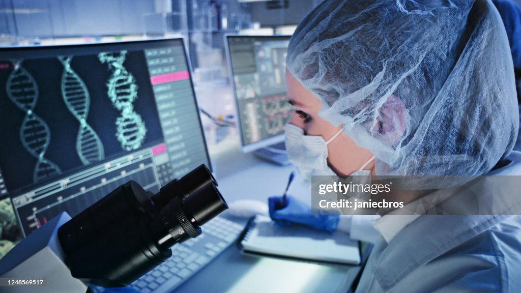 Female doctor studying DNA mutations. Computer screens with DNA helix in foreground