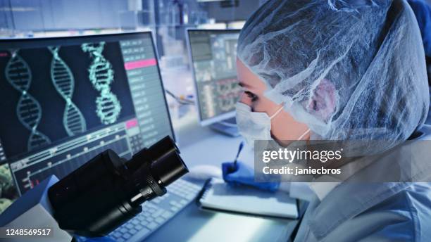 female doctor studying dna mutations. computer screens with dna helix in foreground - dna test stock pictures, royalty-free photos & images