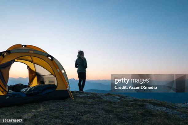 joven observa salida del sol fuera de la tienda de campaña - acampar fotografías e imágenes de stock