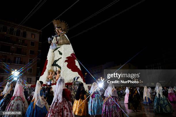 The image has been taken using a star filter on the lens) Falleras dressed up in traditional costume walk past a large model of Saint Mary at the...