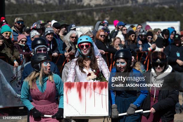 Shannon Carey of Denver, Colorado, holds on as her Bride or Die teammates carry her in a homemade coffin during the coffin races at the Frozen Dead...