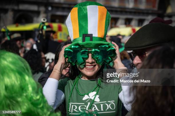 Woman wearing glasses with shamrock shape, symbol of Ireland, celebrating Saint Patrick's Day. More than 300 bagpipers have walked the streets of the...