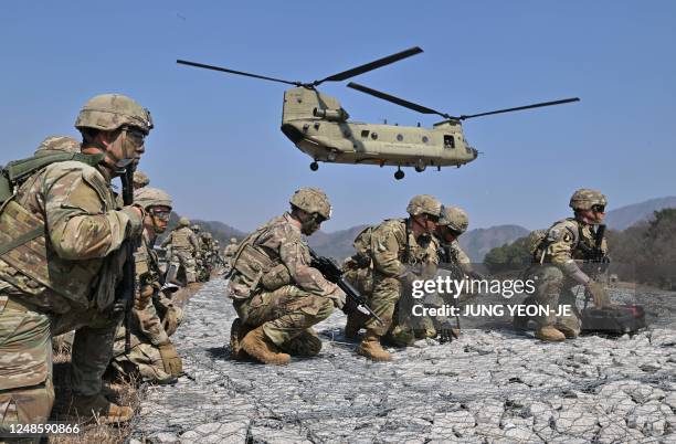 Soldiers take a position as a US Army CH-47 Chinook helicopter prepares to land during a field artillery battalion gun raid drill at a military...