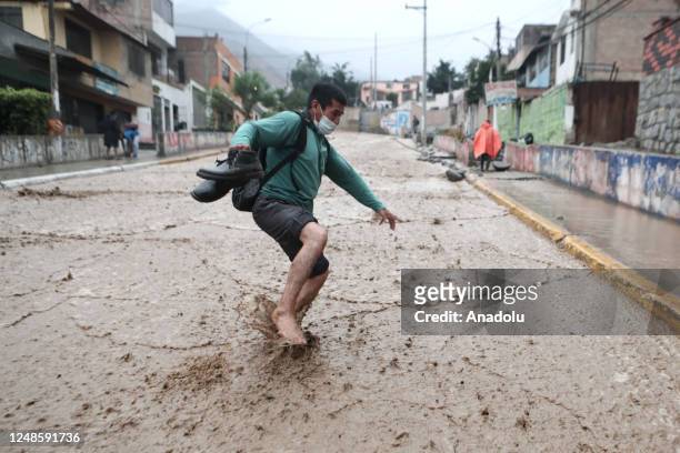 Man cross the tracks due to the strong mudslide caused by heavy rains from Cyclone Yaku in the Chosica district on March 18, 2023