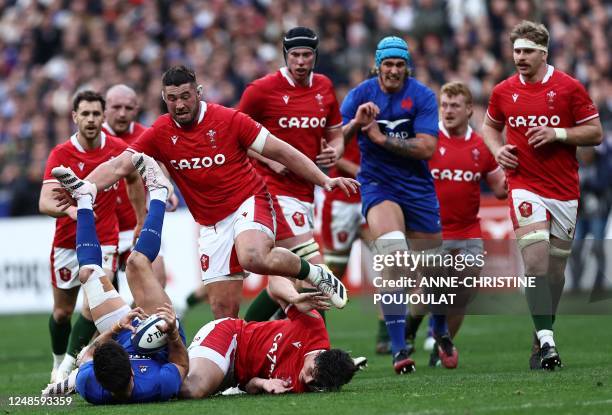 France's fly-half Romain Ntamack holds the ball after tackled by Wales' fullback Louis Rees-Zammit as Wales' prop Gareth Thomas looks on during the...