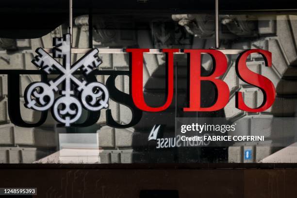 Photograph shows a logo of Swiss giant bank UBS in front of a logo of Credit Suisse bank in Zurich on March 19, 2023. - The heads of Switzerland's...