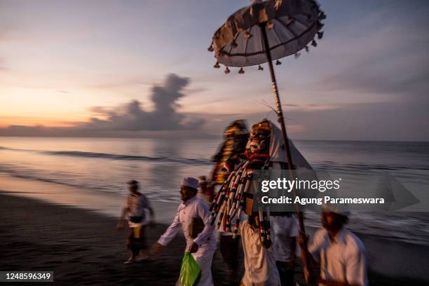 Balinese Hindus man carry sacred mask and sacred effigies during Melasti Ritual prior to Nyepi Day on March 19, 2023 at Siyut Beach, in Gianyar Bali,...