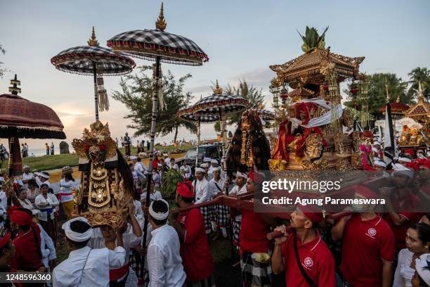 Balinese Hindus people carry ritual paraphernalia and sacred effigies as they arrive on the beach to perform Melasti Ritual prior to Nyepi Day on...