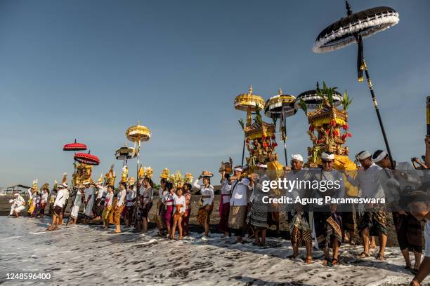 Balinese Hindus people carry sacred mask, sacred effigies and ritual paraphernalia during Melasti Ritual prior to Nyepi Day on March 19, 2023 at...