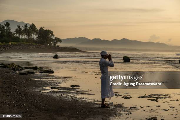 Balinese Hindus man prays as he perform Melasti Ritual prior to Nyepi Day on March 18, 2023 at Masceti Beach, in Gianyar Bali, Indonesia. After three...