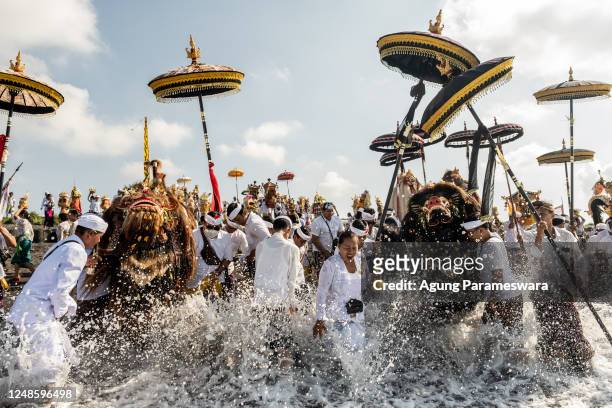 Balinese Hindus people carry sacred mask, sacred effigies and ritual paraphernalia during Melasti Ritual prior to Nyepi Day on March 19, 2023 at...