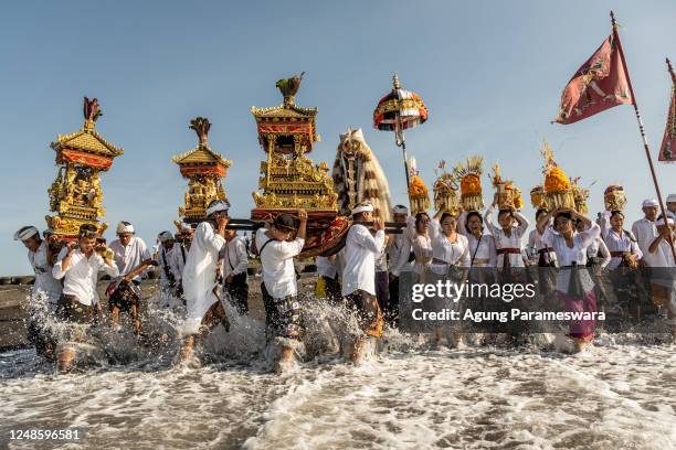 Balinese Hindus people carry sacred mask, sacred effigies and ritual paraphernalia during Melasti Ritual prior to Nyepi Day on March 19, 2023 at...