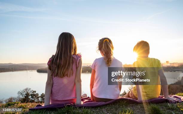 rear view kids enjoying the sunset - triplet girls stock pictures, royalty-free photos & images