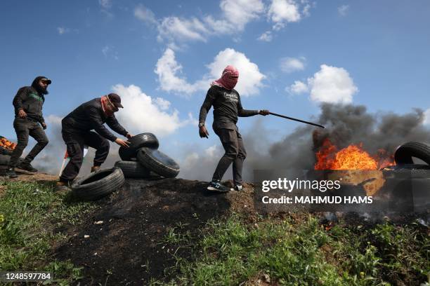 Palestinian protesters burn tyres during a small protest called for by Hamas east of Gaza City by the border with Israel on March 19, 2023 against a...