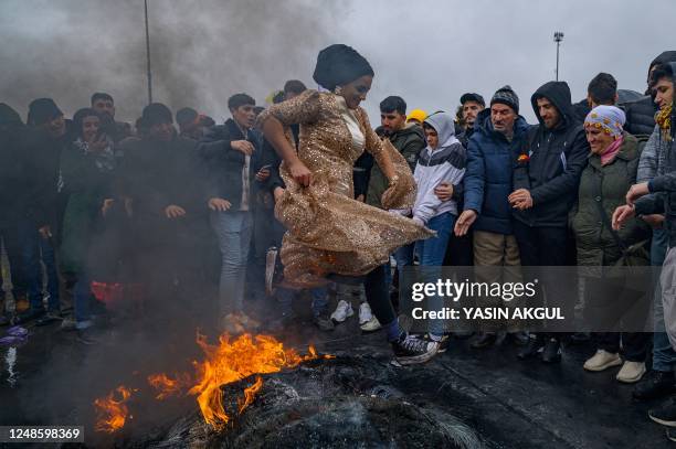 Woman jumps over a bonfire during a Kurdish celebration of Nowruz , the New Year of the Persian calendar, in Istanbul on March 19, 2022.