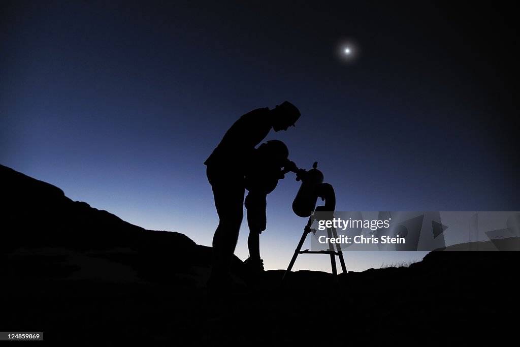 Father and son looking through a telescope