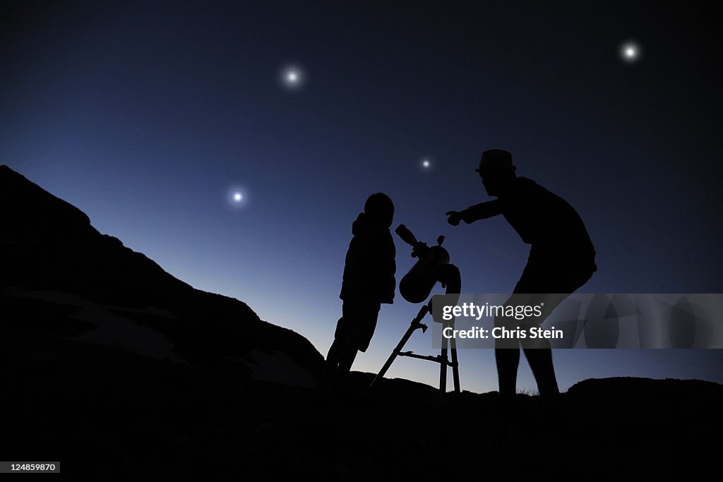 Father and Son looking through a telescope at nigh